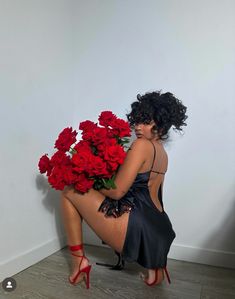 a woman kneeling on the floor with red roses