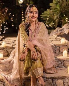 a woman sitting on top of a stone step with candles around her and in the background