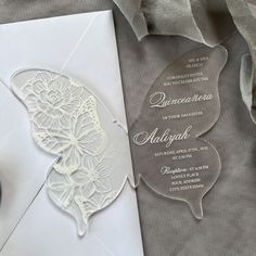 a white wedding card with an intricate butterfly on the front and back, sitting next to a