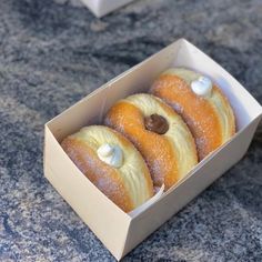 four doughnuts in a box with icing on them sitting on a table