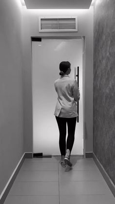 a woman is standing in the hallway with her back to the camera and looking at something