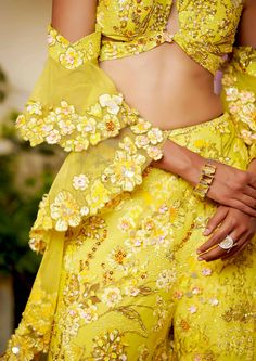 Like walking in a field of flowers where all the flowers bloom under the sun. The energy this co-ord set radiates is incomparable. The joy and comfort of the sun are presented in this set with utter glamour. The flared pants and a top in the shape of a butterfly are paired with a ruffle-sleeved dupatta which ties in the glamour and youth of the dress. Summer Party Palazzo Set With Floral Embroidery, Elegant Floral Print Sharara For Spring, Summer Wedding Sharara, Summer Party Floral Print Sharara, Summer Wedding Palazzo Set With Floral Embroidery, Summer Festive Floral Embellished Sets, Elegant Floral Sets For Summer, Elegant Floral Embellished Sets For Summer, Spring Yellow Lehenga