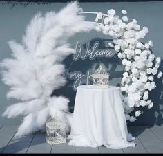 a welcome sign next to a table with flowers and a birdcage on it