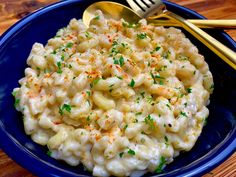 a blue bowl filled with macaroni and cheese on top of a wooden table