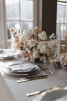 the table is set with flowers and silverware