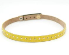 A thin yellow choker made with high quality cowhide leather. Backed with suede and featuring high-shine nailhead studding.Width: 1 cm wide (3/8" wide)Length: 39 cm / 15.5", with adjustable sizing for necks measuring 33 cm / 13” to 37 cm / 14.5”Adjustable metal post closure. Hypo-allergenic, nickel-free.Can be paired with our matching REBELLE Cuff: https://www.etsy.com/ca/shop/Rimanchik?ref=hdr_shop_menu&search_query=yellow+rebelle+cuffThis choker is also available in a variety of other colou Yellow Choker, Metal Post, Choker Designs, Yellow Necklace, Leather Backpack Purse, Modern Watches, Festival Jewelry, Leather Chokers, Leather Cuffs Bracelet