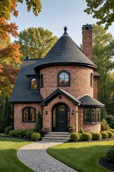 a brick house with a black roof and arched windows in the front yard, surrounded by lush green trees