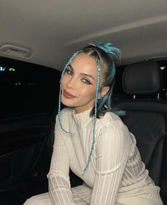 a woman sitting in the back seat of a car with blue hair on her head