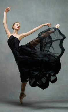 a woman in a black dress is dancing