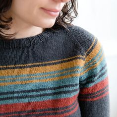 a woman wearing a striped sweater looks off into the distance