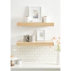 two wooden shelves with pictures and mugs on them in a white tiled kitchen area