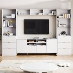 a living room with white furniture and a flat screen tv mounted on a wall unit