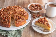 there is a cake on the table with pecans next to it and a cup of coffee