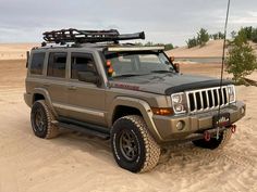 a hummer truck parked in the sand with its lights on and skis strapped to it's roof