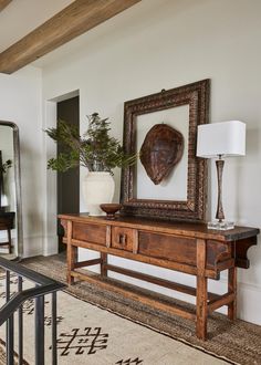 a wooden table sitting in front of a mirror on top of a wall