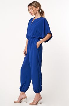 Relaxed sleeves and a tapered, jogger-inspired silhouette amplify the casual-cool style of this go-to jumpsuit. 55" length; 25" inseam; 9" leg opening (size Medium) Hidden front-zip closure Split neck Short sleeves Side-seam pockets Elastic waist Elastic ankle cuffs Unlined 100% polyester Dry clean or hand wash, dry flat Imported Asian Owned/Founded Blue V-neck Relaxed Fit Jumpsuits And Rompers, Blue V-neck Relaxed Fit Jumpsuit, Blue Jumpsuits And Rompers With Elastic Waistband For Spring, Relaxed Fit Jumpsuits With Elastic Waistband For Work, Ankle Cuffs, Cool Style, Elastic Waist, Top Brands, Split