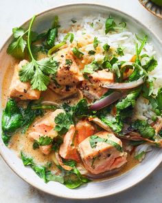 a white plate topped with fish and rice covered in cilantro, green garnish