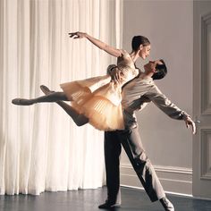 a man and woman are dancing together on the dance floor in front of white curtains