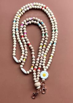 a white beaded necklace with a flower and two pairs of scissors hanging from it