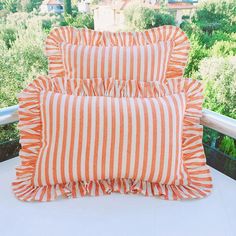 three orange and white striped pillows on a balcony