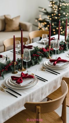 the table is set for christmas dinner with candles and decorations