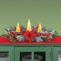 a christmas centerpiece with pine cones, holly and poinsettis on top