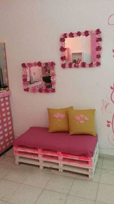 a bed made out of pallets in a room with pink and yellow decorations on the walls