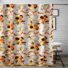 a shower curtain with an orange and yellow flower pattern on the outside, hanging from a white brick wall