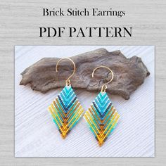 a pair of earrings made out of seed beads on top of a piece of wood