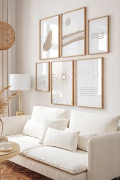 a living room with white couches and pictures on the wall above them in gold frames