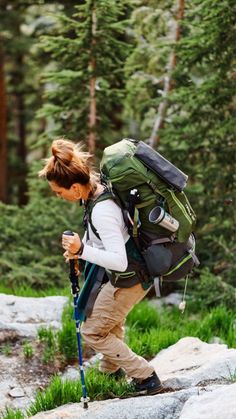 a woman hiking in the woods with a backpack and trekking poles on her back