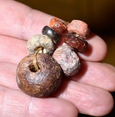 a hand holding several different colored rocks in it's palm, including one with a ring