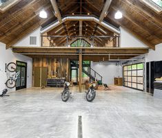 two motorcycles are parked in the middle of a large room with high ceilings and wooden beams