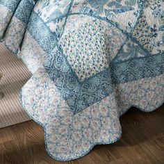 a blue and white quilted bedspread sitting on top of a wooden floor