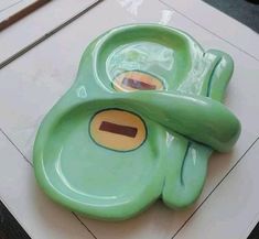 a green frog shaped plate with two holes in it