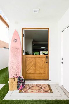 a pink surfboard sitting next to a wooden door