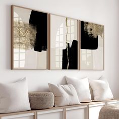 three paintings hanging on the wall above a bench with white pillows and throw pillows in front of them