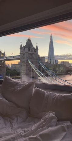 a bed sitting in front of a window with a view of the bridge and buildings