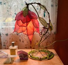 a table topped with a vase filled with flowers next to a window covered in curtains