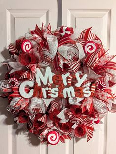 a red and white christmas wreath with candy canes hanging on the front door to say merry christmas