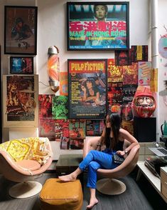 a woman sitting in a chair with posters on the wall behind her and other decorations around her