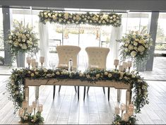 two chairs sitting on top of a table covered in flowers and greenery next to each other