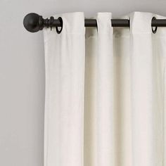 white curtains hanging on the side of a window with black hardware and curtain roding