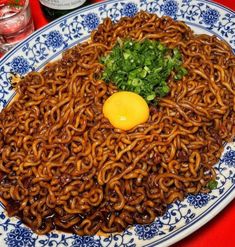 a plate with noodles and an egg on it, sitting on a red tablecloth