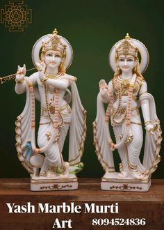 two statues of hindu god and goddess standing next to each other on a wooden table