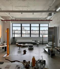 an empty room with tables and couches in front of a large window that overlooks the city