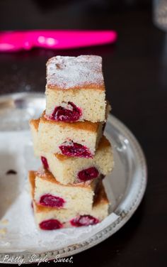 three pieces of cake on a plate with powdered sugar and raspberry topping