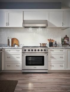 a stove top oven sitting inside of a kitchen next to white cabinets and counter tops