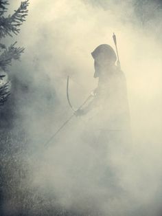 a person with a bow and arrow in the fog