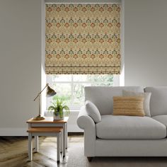 a living room scene with focus on the couch and window blinds that have an intricate pattern